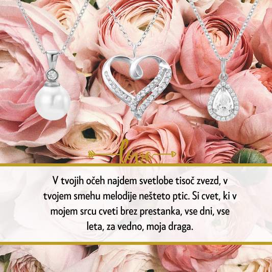 Personalizirana srebrna verižica z vgraviranim imenom in datumom, obdana z majhnimi kristali, kot idealno darilo za Dan žena. Elegantna darilna škatla na beli podlagi z rdečo vrtnico ob strani, simbolizira ljubezen in spoštovanje na poseben dan